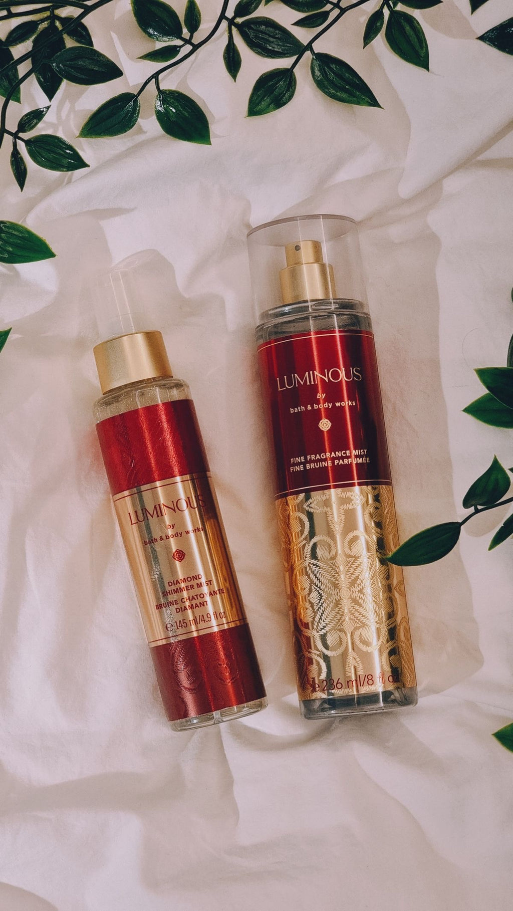 eliteessence Luminous Diamond Shimmer Mist and Fine Fragrance Mist bottles with gold accents on white fabric
